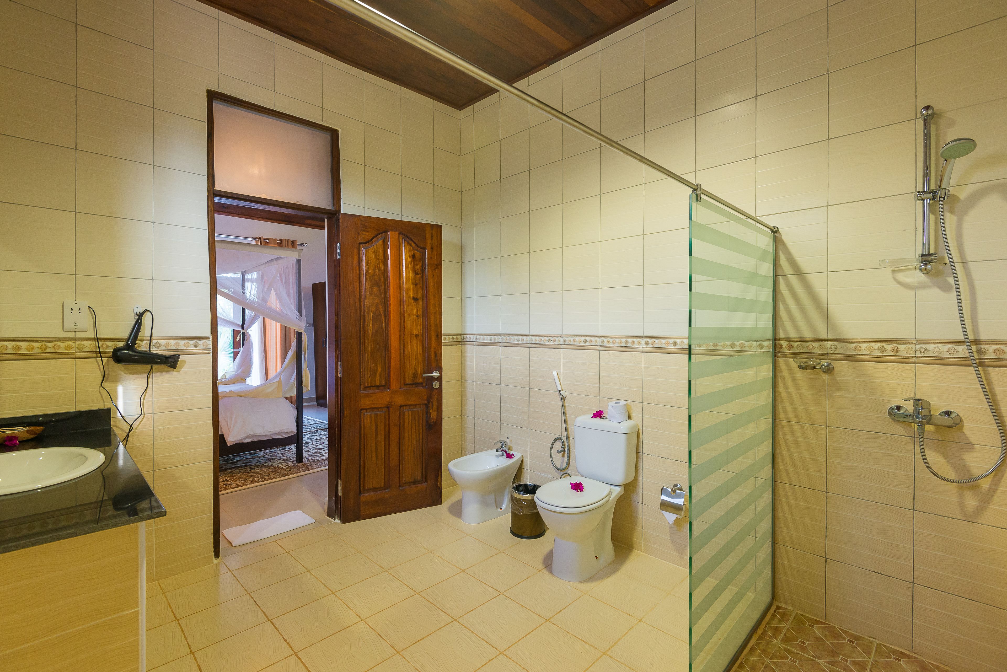 A bathroom with a shower, toilet, bidet, and sink.