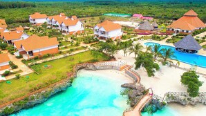 Ein Resort mit mehreren bungalowartigen Gebäuden, einem zentralen Schwimmbad und einer Strandfläche.