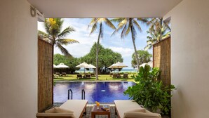 A poolside area with lounge chairs and umbrellas, a view of a pool, and tropical vegetation. - Ekho Surf (Bentota)
