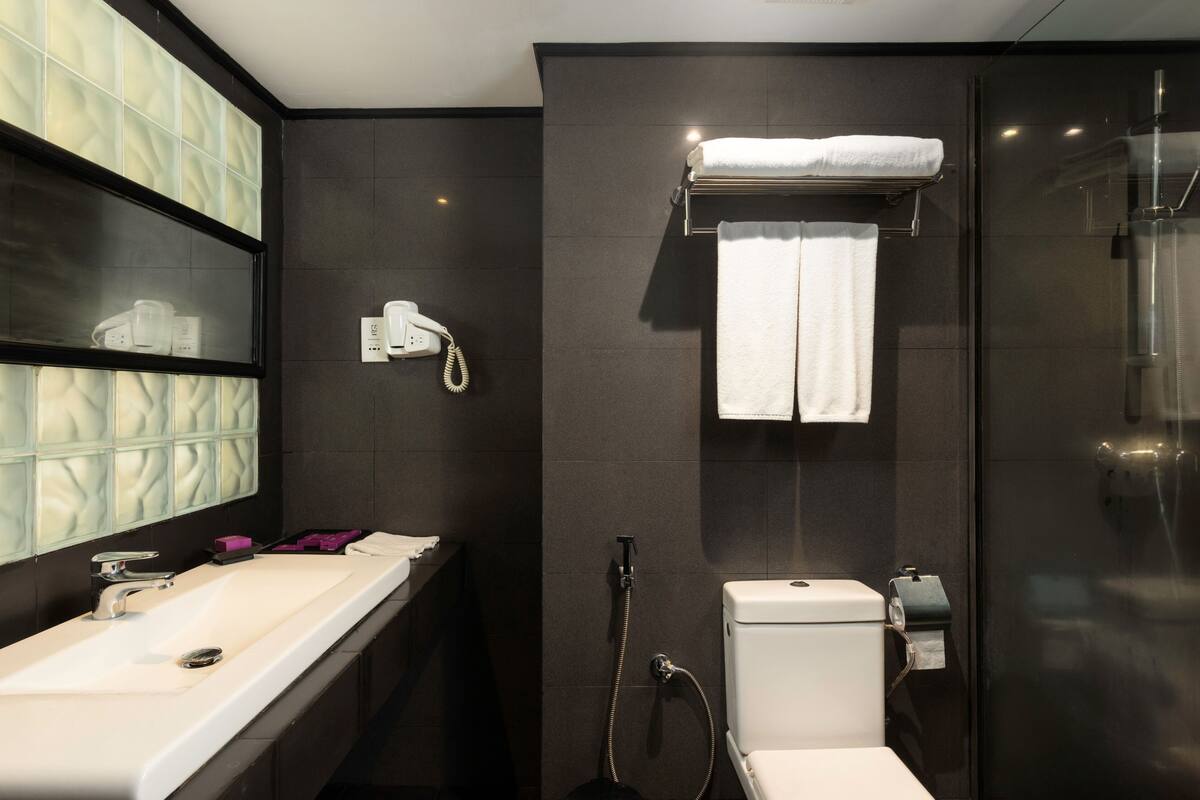 A modern bathroom with a large mirror, a sink, a toilet, and a shower area.