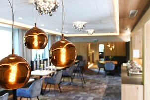 A modern interior with hanging spherical light fixtures, a dining area with chairs, and a reception desk.
