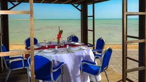An outdoor dining area with a table set for four, overlooking a beach.