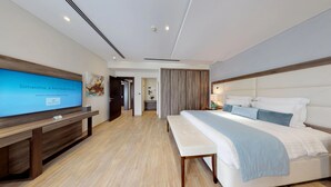 A modern hotel room with a large bed, a bedside table, a TV, and a wooden desk.
