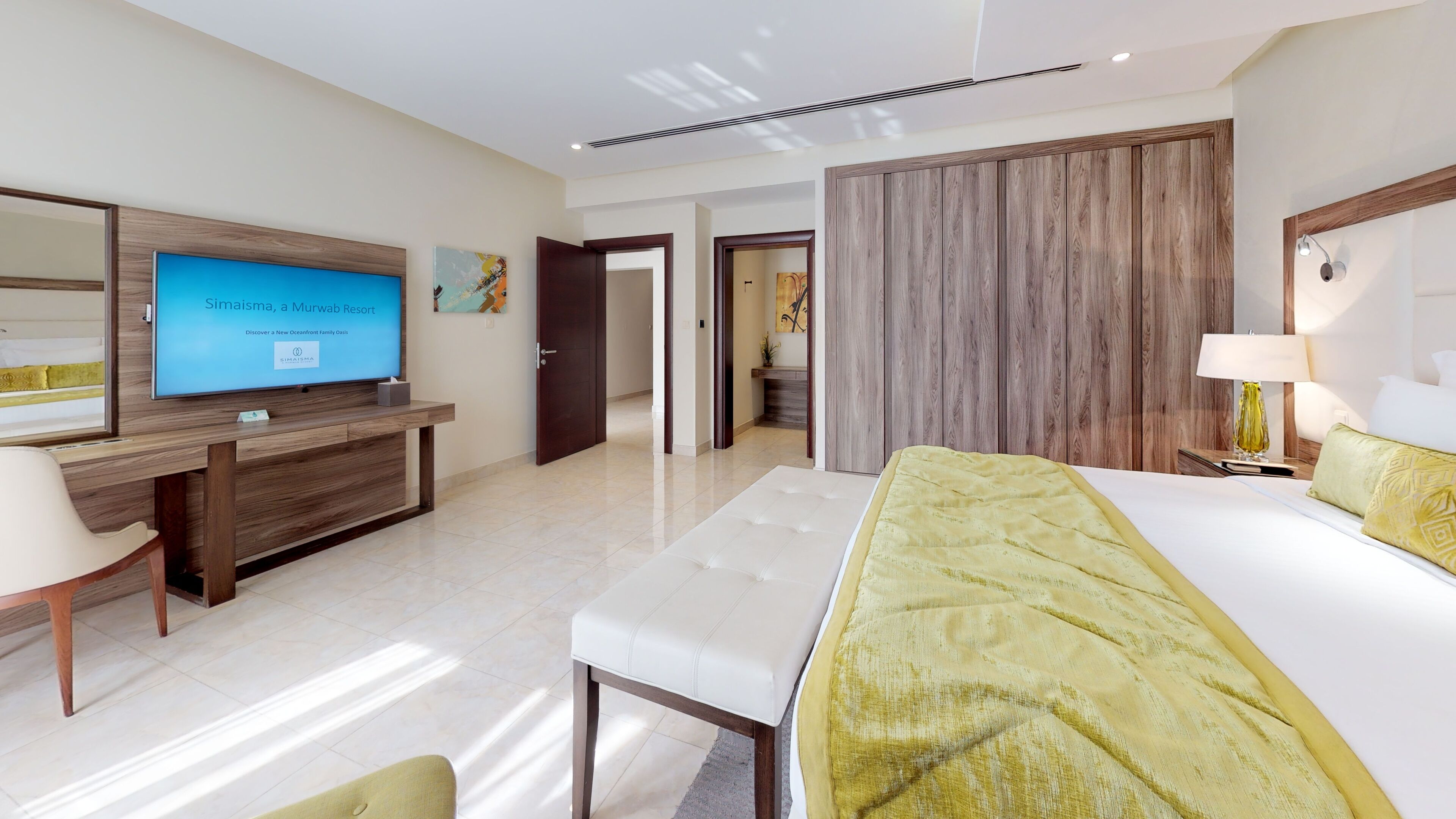 A hotel room with a bed, a desk with a TV, a chair, and a large window.