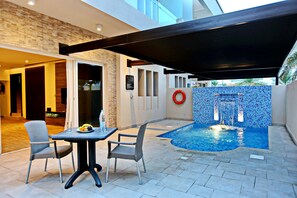 Une terrasse extérieure avec une piscine, une table et des chaises, ainsi qu’un espace abrité.