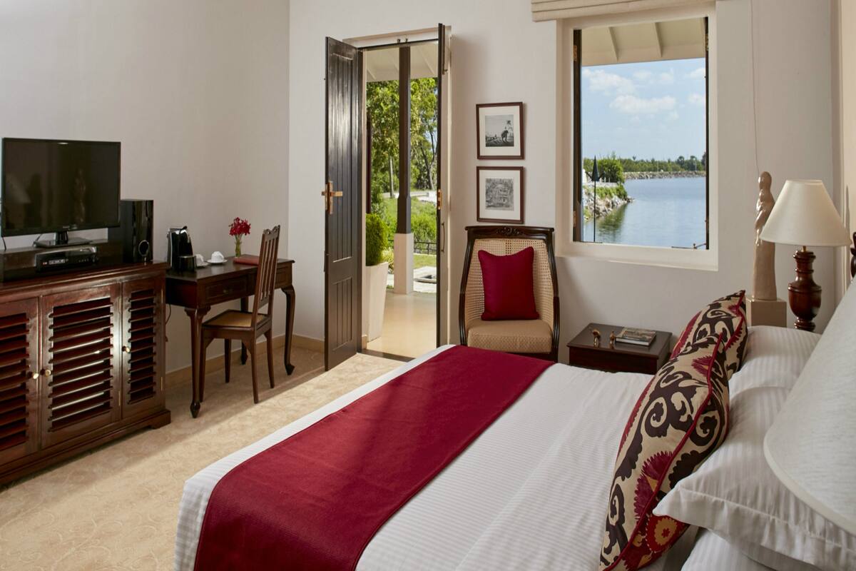 Une chambre d’hôtel équipée d’un lit, d’un bureau, d’une télévision et d’une fenêtre donnant sur un plan d’eau.