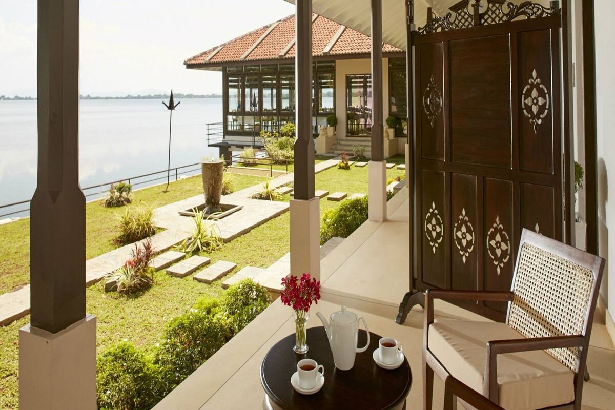 Une terrasse avec une table et des chaises, une vue sur la mer et, au fond, un bâtiment avec un toit en tuiles.