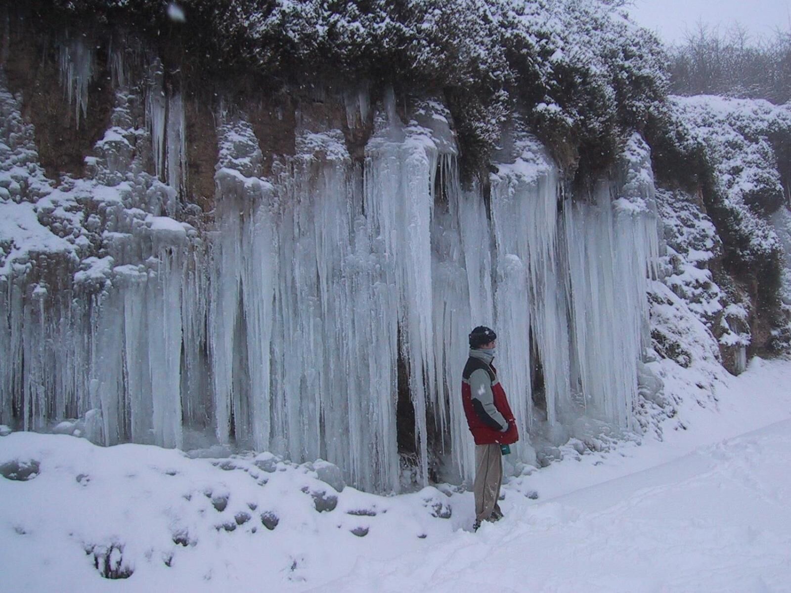 A person standing in front of a large ice formation.