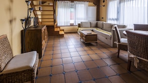 A cozy living room with a sofa, a wicker chair, a small table, and a staircase leading to an upper level. - CTR La Coruja del Ebro (Valderredible)