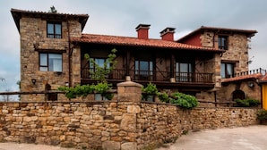 A stone building with a red-tiled roof, multiple balconies, and a stone wall surrounding the property. - CTR La Coruja del Ebro (Valderredible)