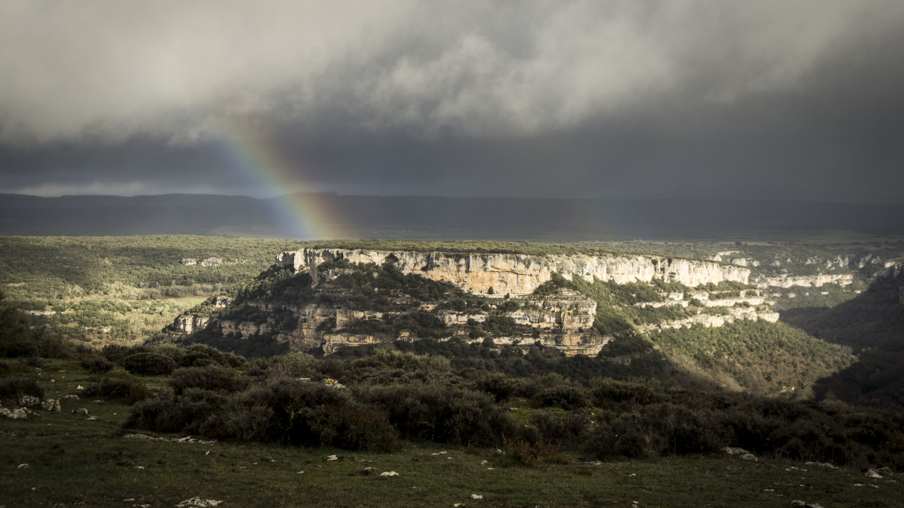 Un paisaje con una imponente formación rocosa y un arcoíris.
