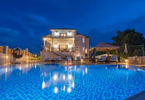 A swimming pool with a view of a two-story building with a balcony and outdoor seating area.