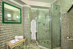 A bathroom with a glass-enclosed shower, a bench with towels, and a mirror with a green frame. - Frido Luxury Villa (Zakynthos)