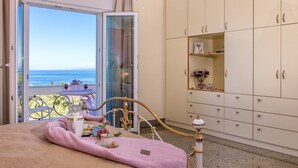 Un dormitorio con cama, balcón con mesa y armario.