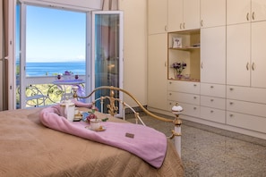 A bedroom with a bed, a balcony with a table, and a wardrobe. - Frido Luxury Villa (Zakynthos)