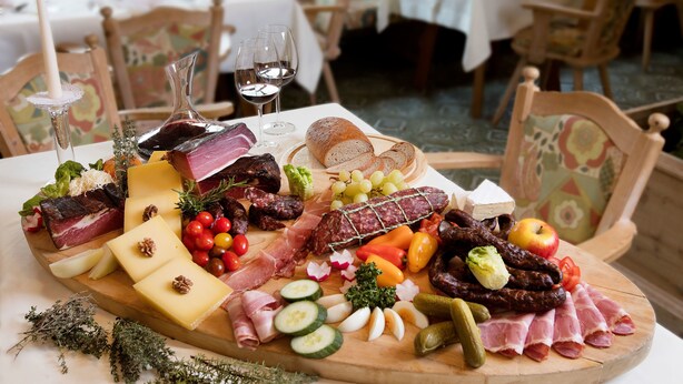 Een plank met verschillende vleessoorten, kazen en fruit.