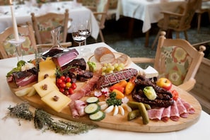 A charcuterie board with various meats, cheeses, and fruits on a wooden board. - Bergidyll & Hotel Trofana (Leutasch)