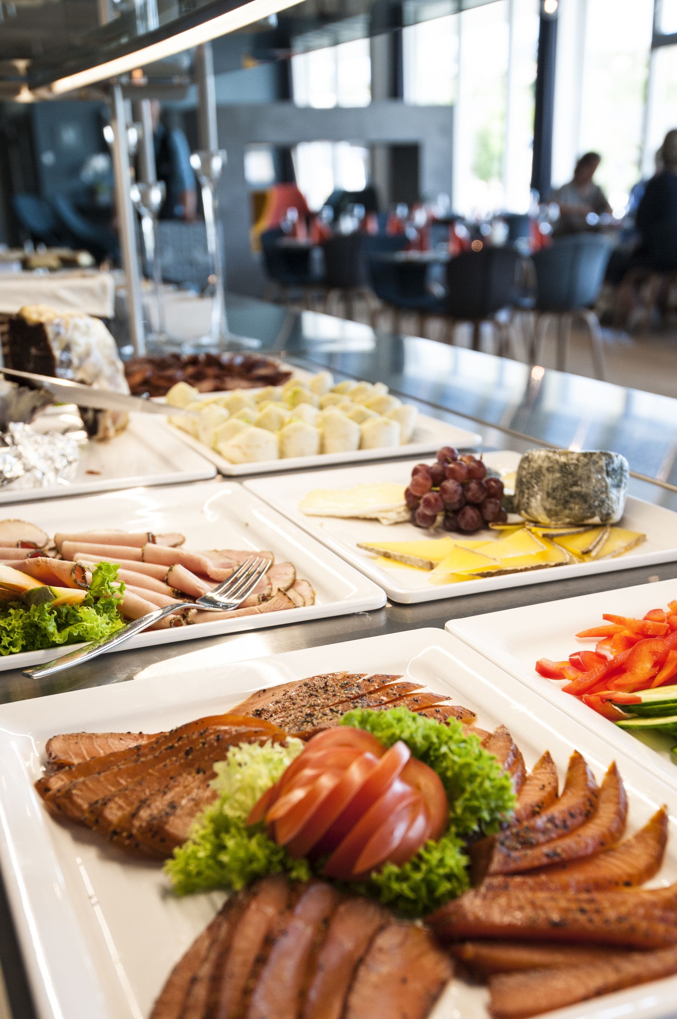 A buffet with various food items including meats, cheeses, and vegetables.