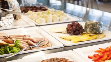 A buffet with various food items including meats, cheeses, and vegetables.