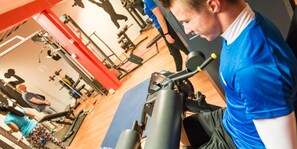 Un gimnasio con equipo de ejercicio y una persona usando una máquina.