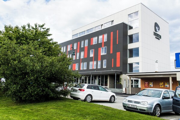Un bâtiment moderne doté d’un toit plat, de nombreuses fenêtres et d’une enseigne indiquant qu’il s’agit d’un hôtel.