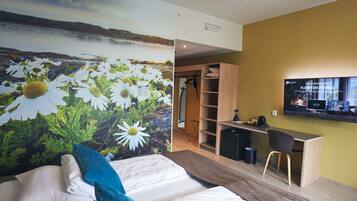 Una habitación de hotel con una cama, un escritorio y un televisor.