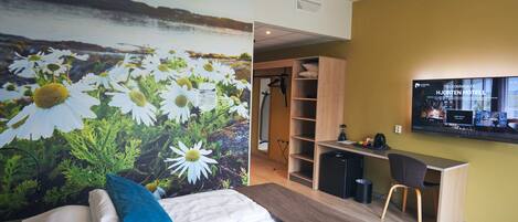 A hotel room with a bed, a desk, and a TV.