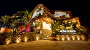 Um hotel moderno com fachada de pedra, uma escadaria visível e uma placa com o dizer 'Hotel Oceanic'.