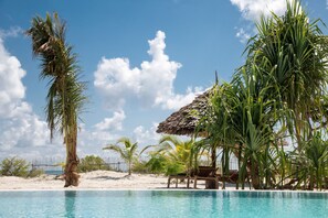 Una piscina al aire libre, sombrillas, sillones reclinables de piscina
