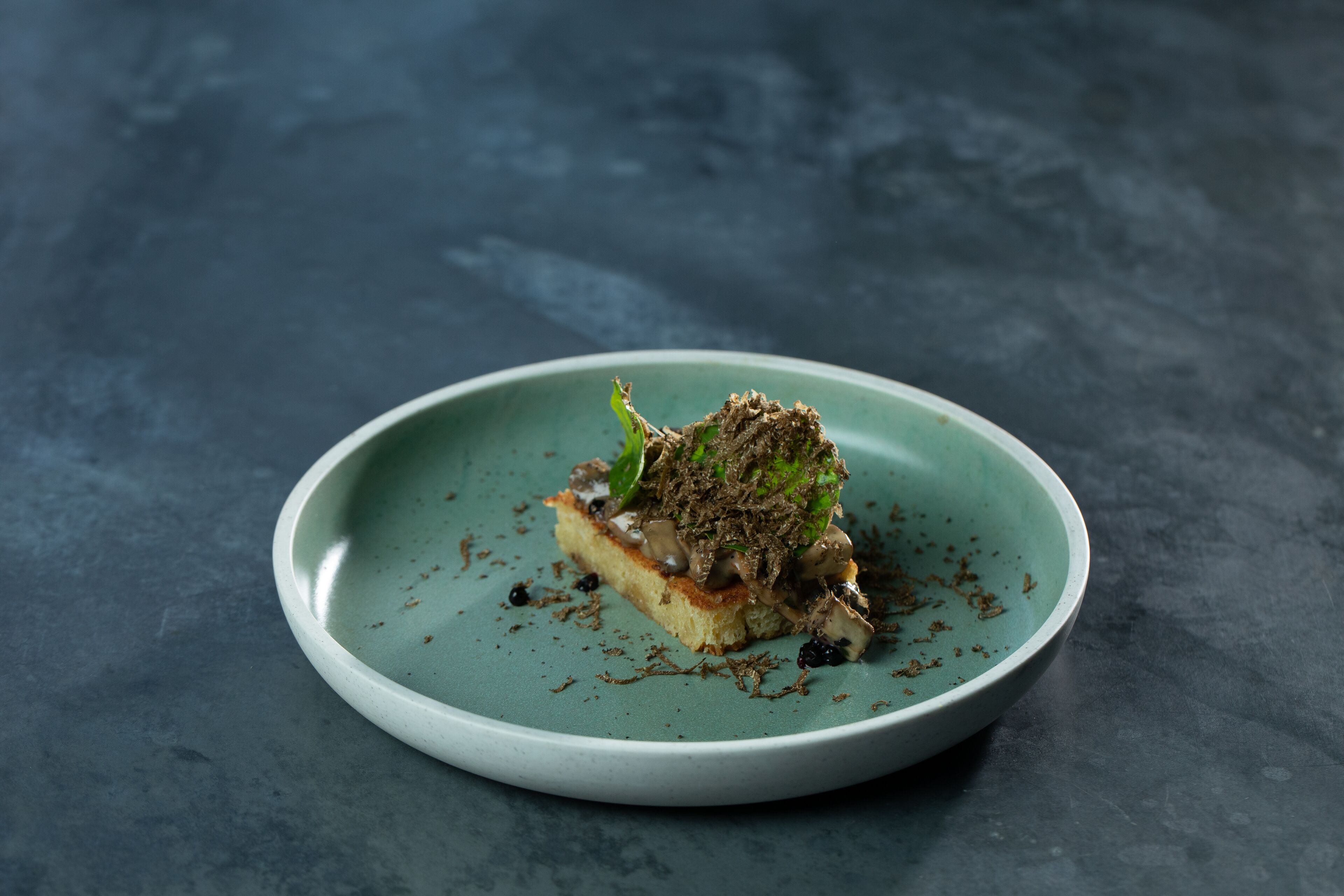 A plate with a piece of food on a textured surface.