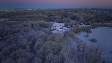 A snow-covered landscape with a building complex surrounded by trees.