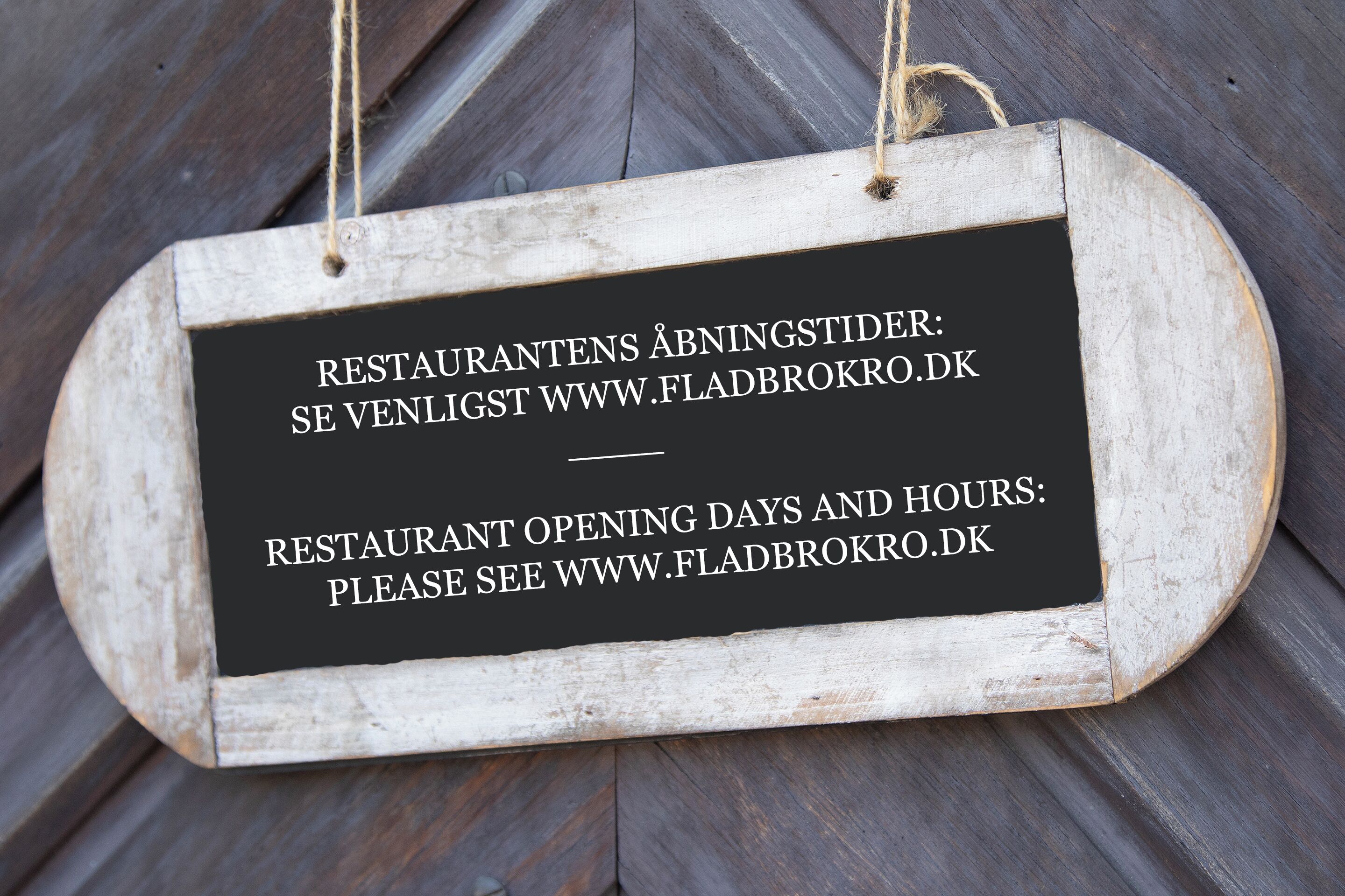 Un letrero de madera con información sobre los días y horarios de apertura de un restaurante.