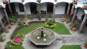 A courtyard with a central fountain, surrounded by potted plants and a flag. - Hotel + Arte (Quito)