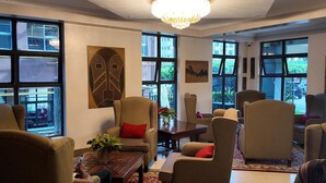 A spacious room with large windows, a chandelier, and several armchairs. - The Luke Hotel (Nairobi)
