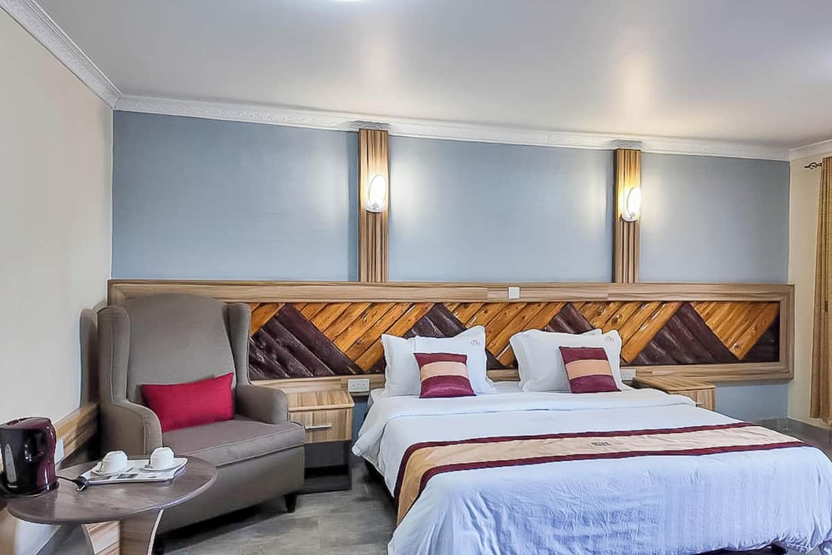 A hotel room with a bed, a chair, a bedside table, and a nightstand.