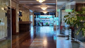 A hotel lobby with a marble reception desk, a chandelier, and a glass partition with a plant. - The Luke Hotel (Nairobi)