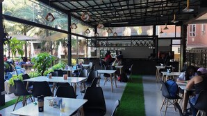 An outdoor cafe with tables and chairs, a counter, and a view of palm trees. - The Luke Hotel (Nairobi)