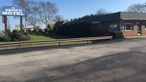 A motel with a sign reading "GENE'S MOTEL," a brick building, and a small office.
