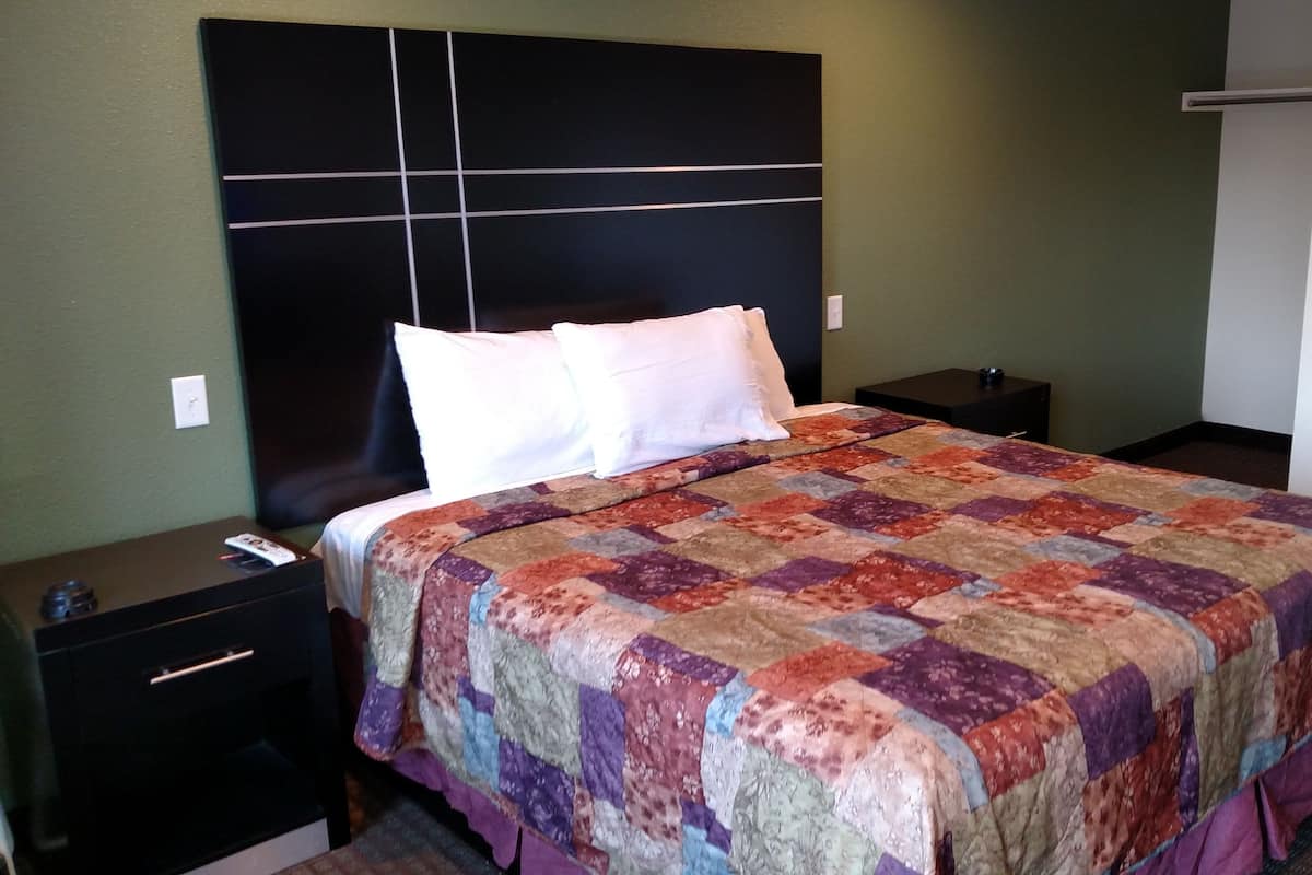 A hotel room with a large bed, a headboard, two bedside tables, and a nightstand.
