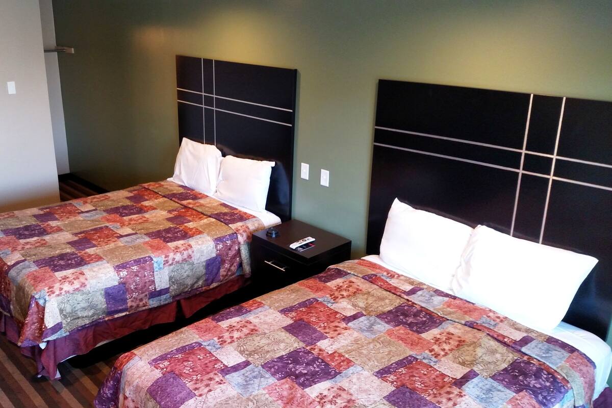 Two twin beds with matching headboards and nightstands, a striped carpet, and a plain wall.