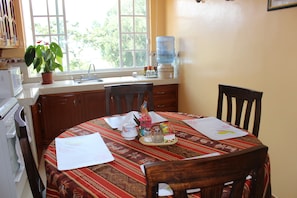 A kitchen with a dining table, chairs, a microwave, a water dispenser, and a potted plant. -  Casa de Huéspedes Casa de Luis (San Pablo del Lago)