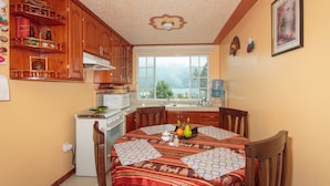 A kitchen with wooden cabinets, a stove, and a dining table with a tablecloth. -  Casa de Huéspedes Casa de Luis (San Pablo del Lago)