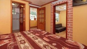 A room with a patterned carpet, a bed, a wooden door, and a brick wall. -  Casa de Huéspedes Casa de Luis (San Pablo del Lago)