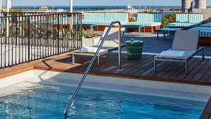 Zona de piscina con sillones de descanso y vista al mar.