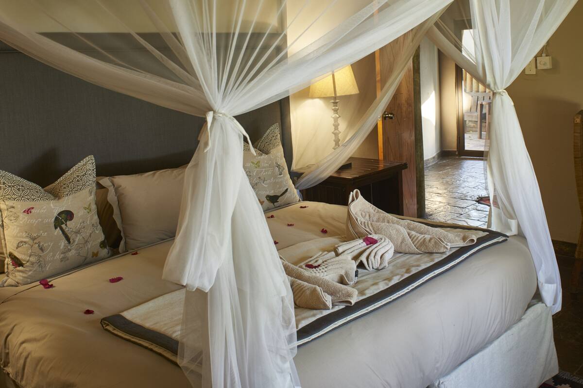 A bed with a canopy, pillows, and a bedside table with a lamp.
