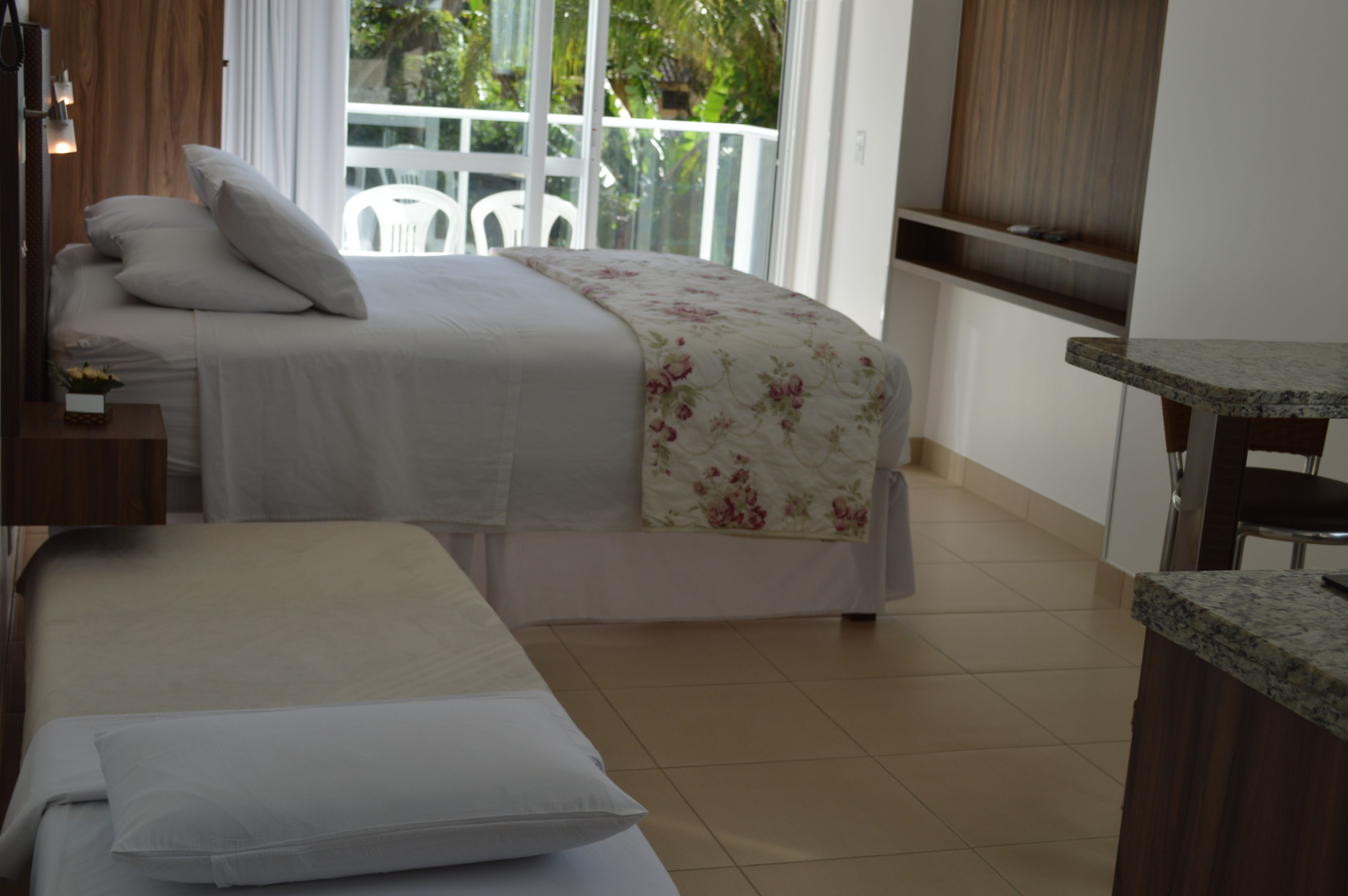 A bedroom with a bed, a bedside table, and a small table with a chair.