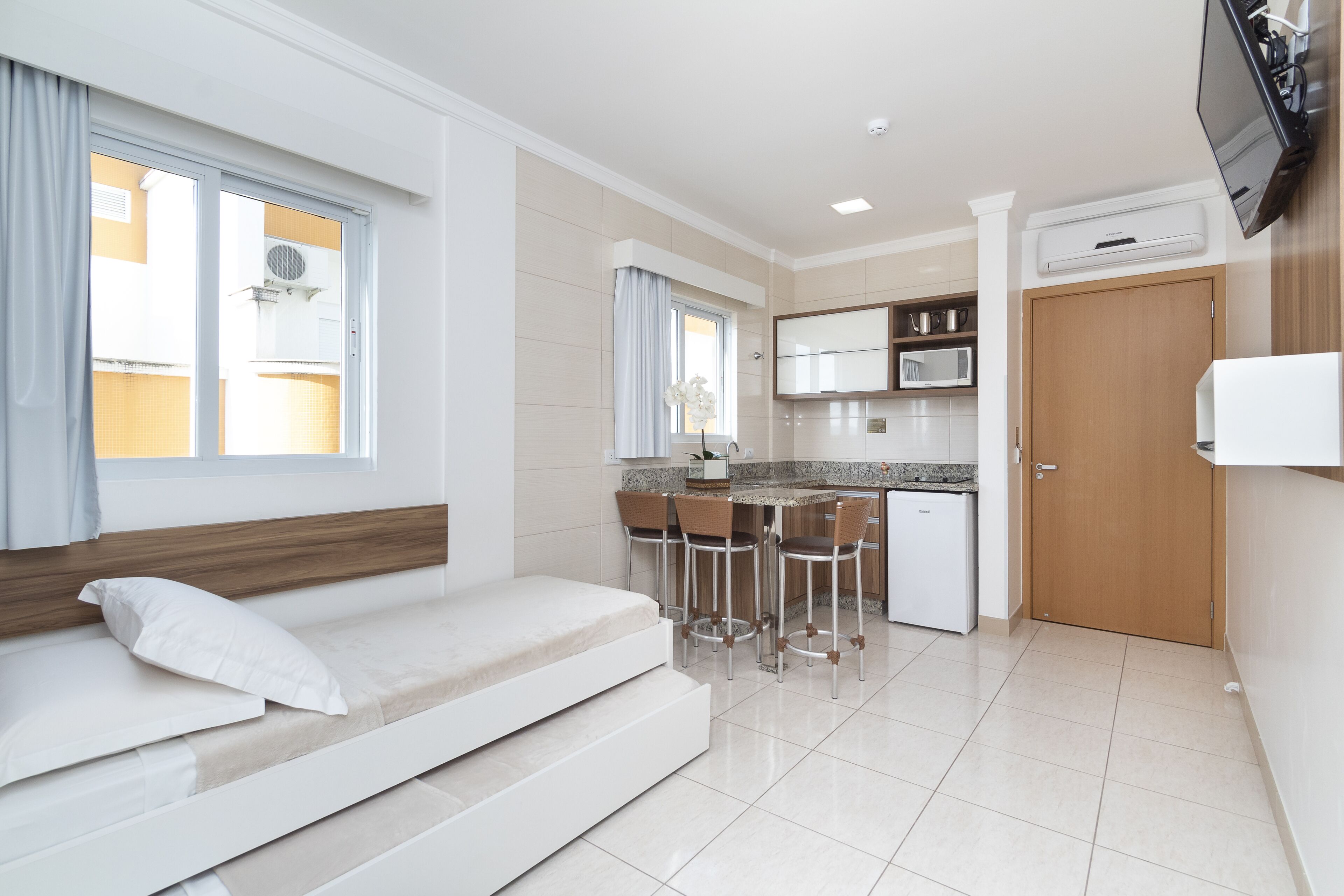 Un espacio habitable compacto con sofá cama, kitchenette y comedor.
