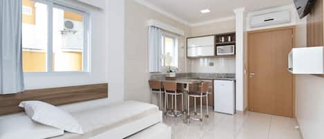 Un espacio habitable compacto con sofá cama, kitchenette y comedor.