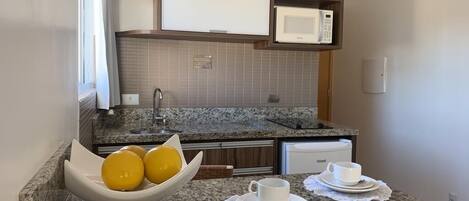 A modern kitchen with granite countertops, a built-in microwave, and a bowl of lemons.