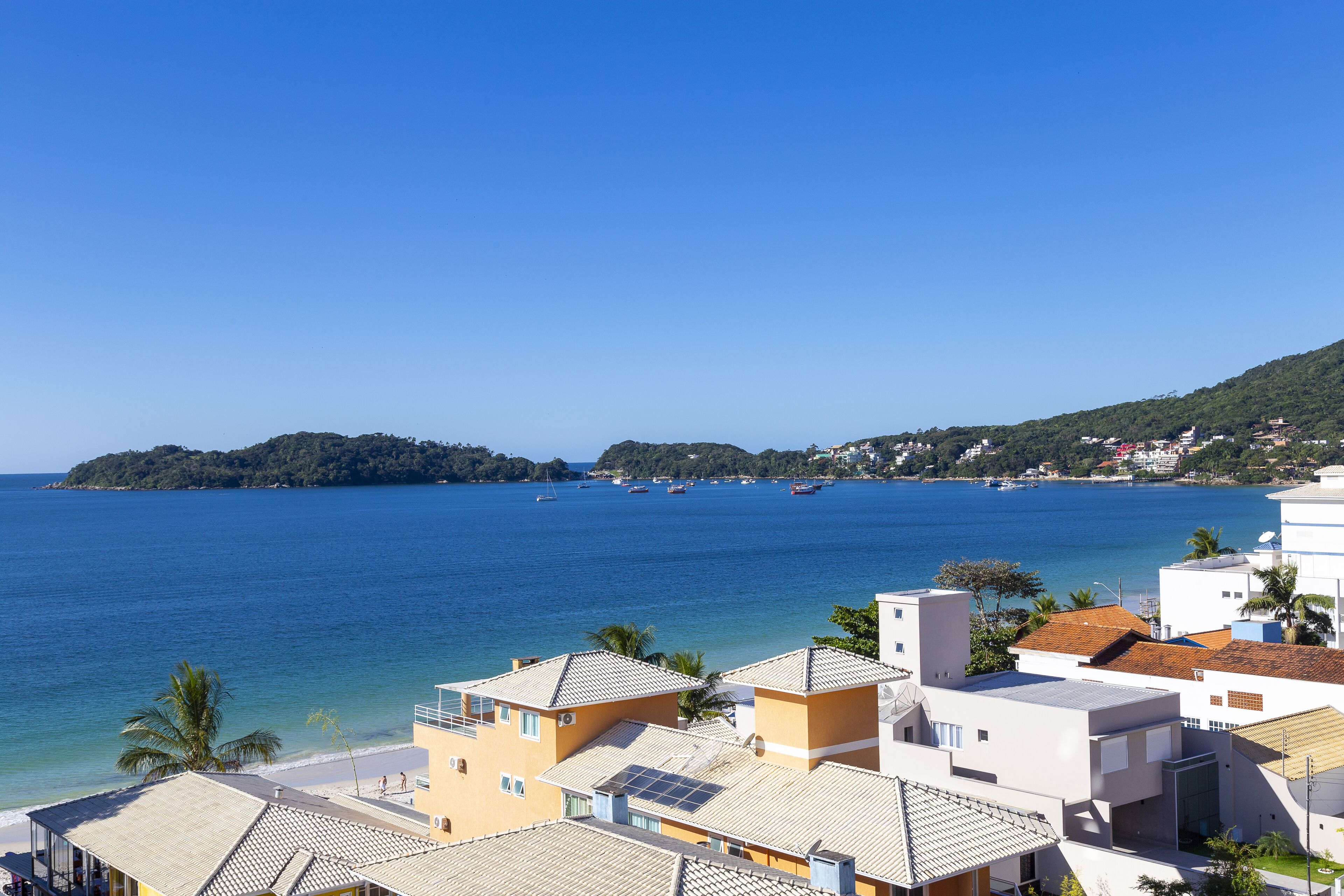 A coastal town with buildings overlooking a clear blue sea, featuring a mix of modern and traditional architecture.